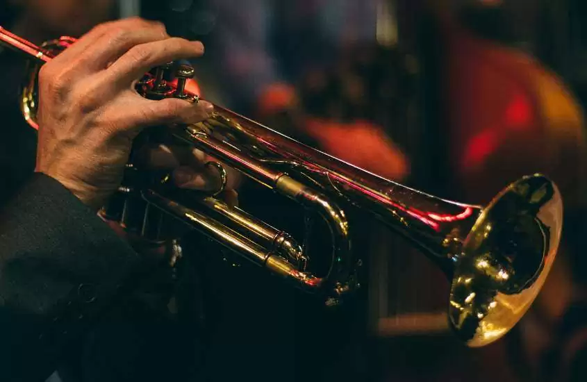 mão de pessoa segurando trompete dourado em clube, atrativo para quem busca o que fazer em nova york a noite