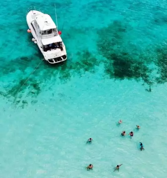 durante o dia, vista aérea de pessoas nadando em mar azul, perto de lancha branca, em praia de cozumel méxico