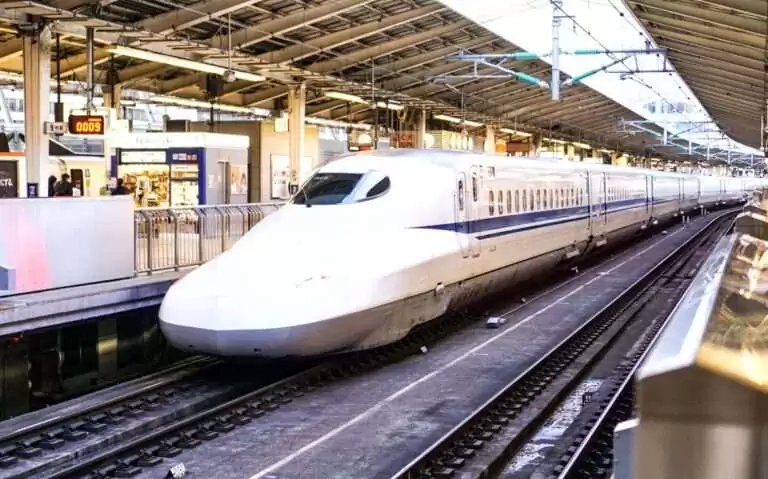durante o dia, trem-bala branco com listra azul em estação de trem no japão