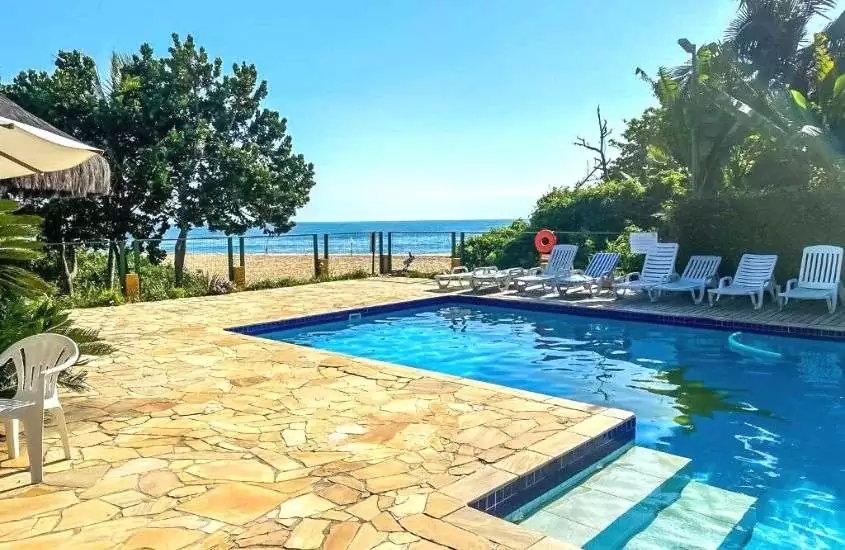 durante dia ensolarado, espreguiçadeiras brancas em frente a piscina ao ar livre, com vista para o mar
