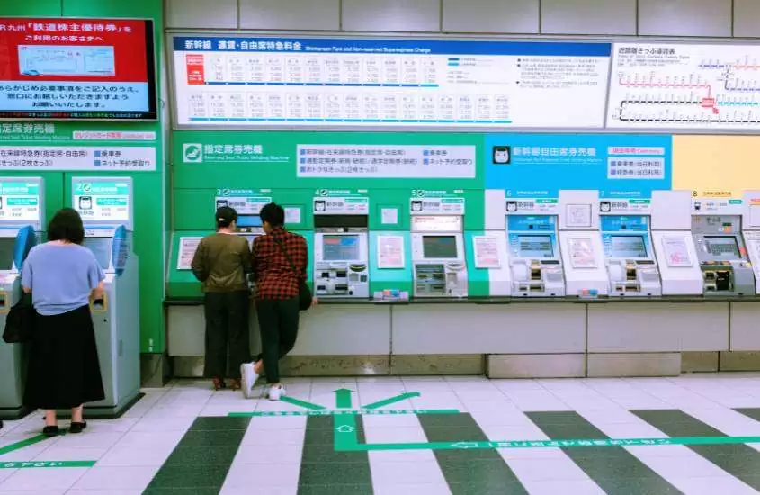 pessoas de costas comprando passagem de trem no japão em máquina