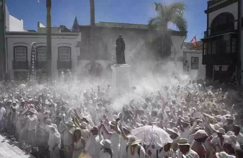 durante o dia, diversas pessoas vestidas de branco, jogando talco para o alto em festival da cultura espanhola