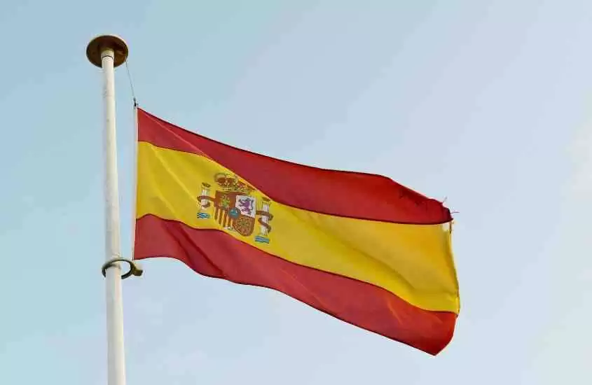 durante o dia, bandeira com faixas horizontais vermelhas e amarela hasteada em rua da espanha
