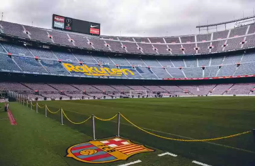durante dia nublado, arquibancada vermelha e azul e gramado verde em estádio de futebol, esporte popular na cultura espanhola