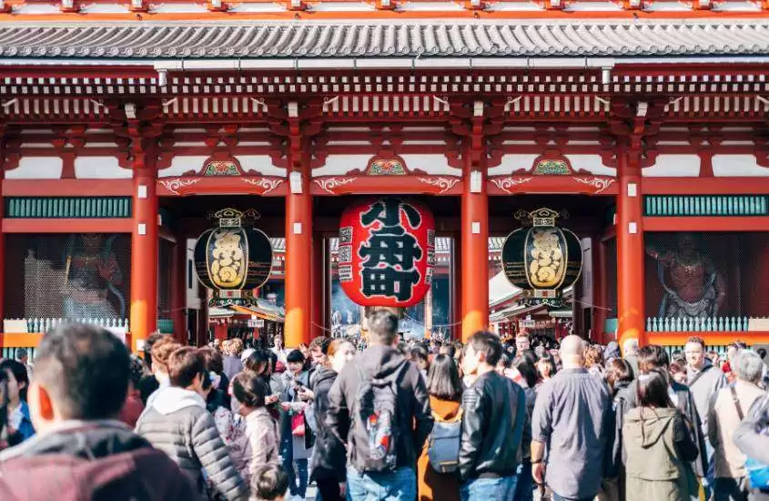 durante o dia, diversas pessoas caminhando em área externa de templo japonês