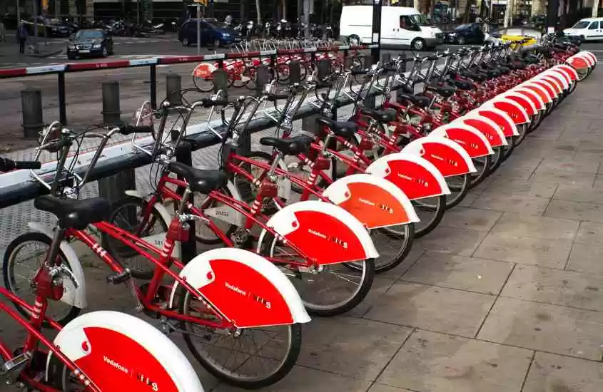durante dia, diversas bicicletas vermelhas e brancas usadas por quem faz turismo em Barcelona
