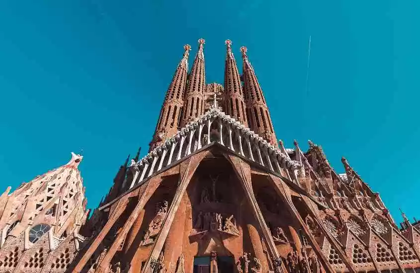 durante o dia, vista de baixo para cima de fachada de igreja em estilo neogótico que é um dos pontos turísticos de Barcelona