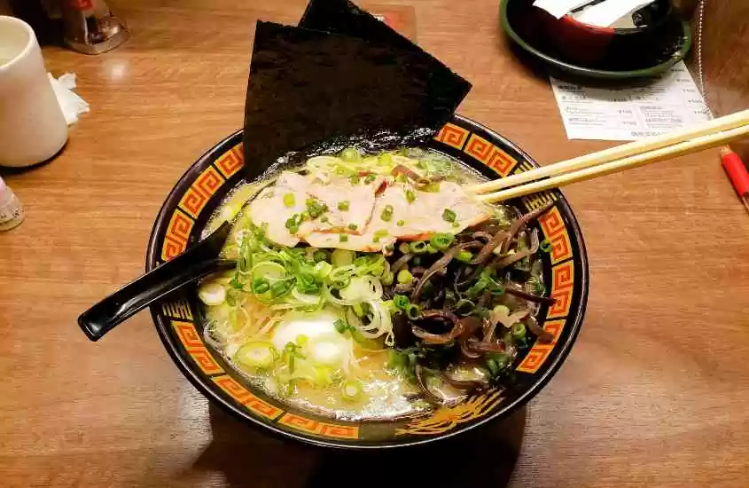 prato redondo, com comida japonesa, em cima de mesa de madeira