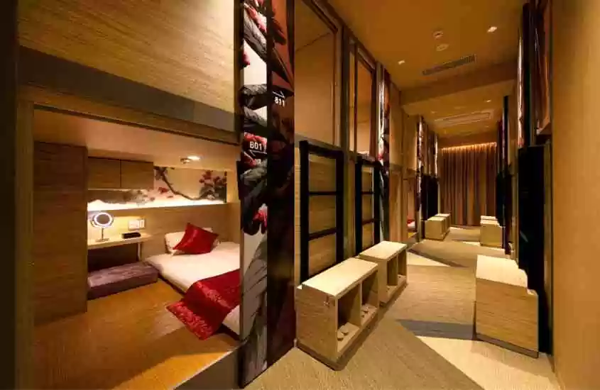 corredor de hotel com diversas cápsulas equipadas com colchão de solteiro