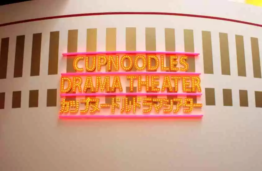 letreiro amarelo escrito 'cup noodles drama theater' em museu