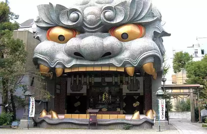 durante o dia, escultura de um leão com a boca aberta em entrada de templo, um dos pontos turísticos de Osaka