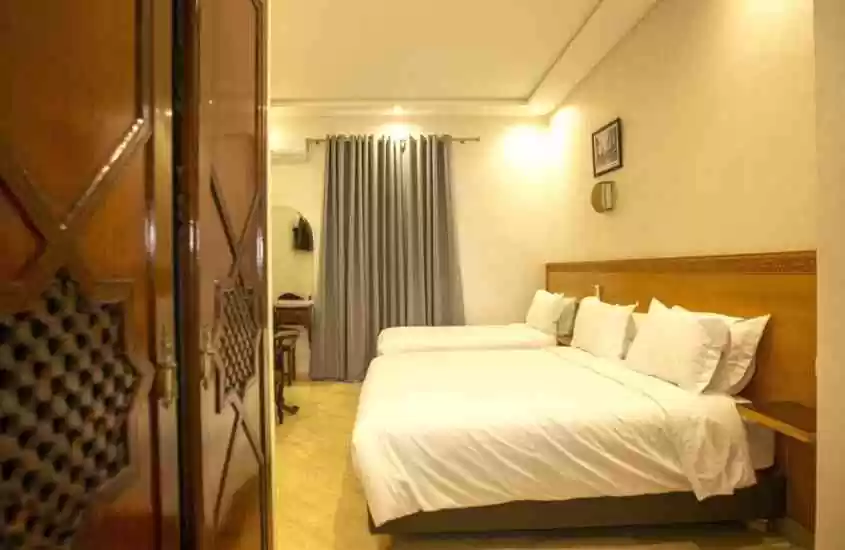duas camas de casal e guarda-roupa de madeira em suíte de hotel em casablanca