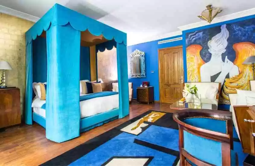 abajur em cima de mesa de cabeceira, cama de casal com cortina azul e tapete estampado em suíte de hotel em Casablanca