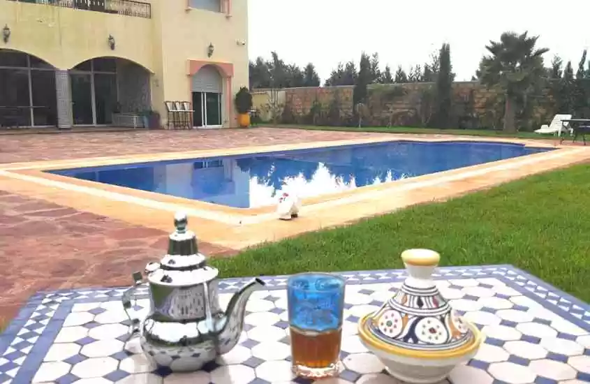 durante o dia, chá servido em frente a grande piscina retangular ao ar livre em quintal de riad em casablanca