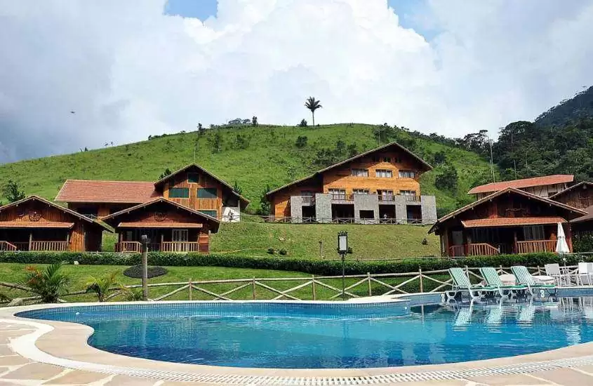 durante dia nublado, piscina ao ar livre em quintal em frente a montanhas com diversos chalés de madeira