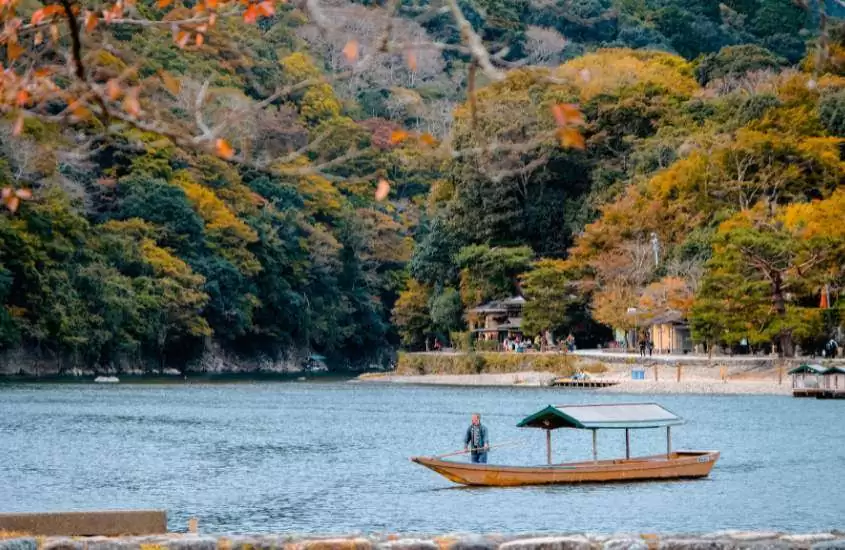 durante o dia, pessoa em canoa em rio cercado por árvores em arashiyama, um lugar onde se hospedar em kyoto
