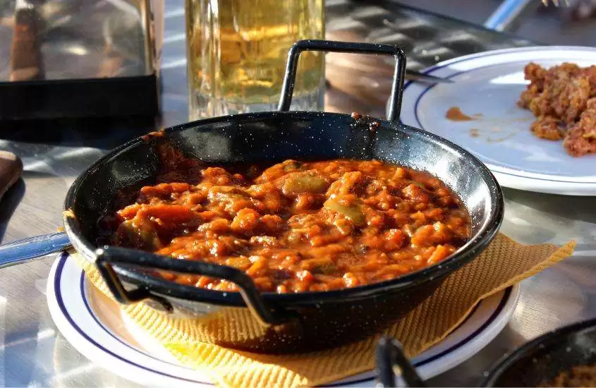 vasilha preta redonda com pisto, comida tipica da espanha que é uma mistura de legumes frescos