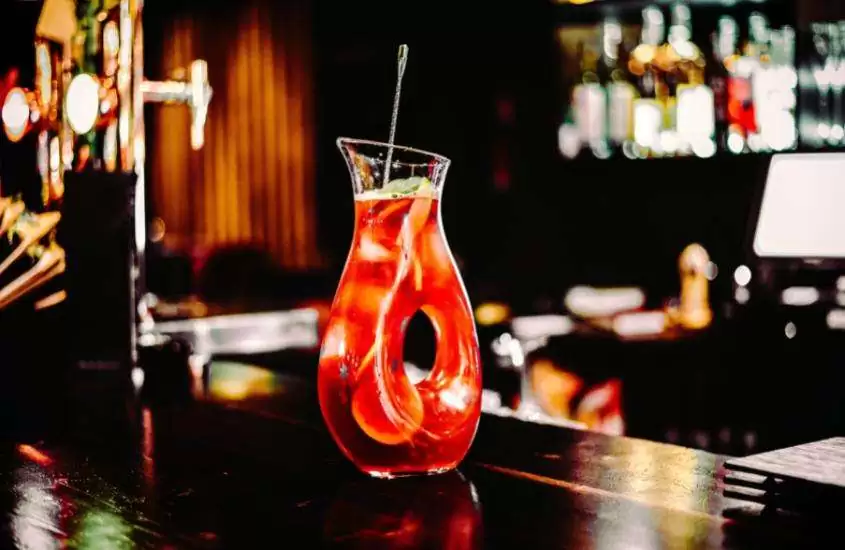 garrafa de vidro com sangria, uma bebida alcoólica típica da Espanha feita com vinho, frutas e especiarias, disposta em cima de um balcão de bar