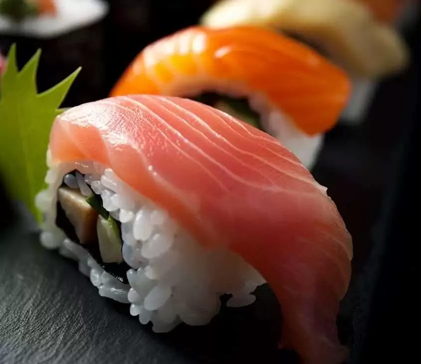 Um pedaço de sushi com arroz, peixe e nori, servido em uma tigela preta