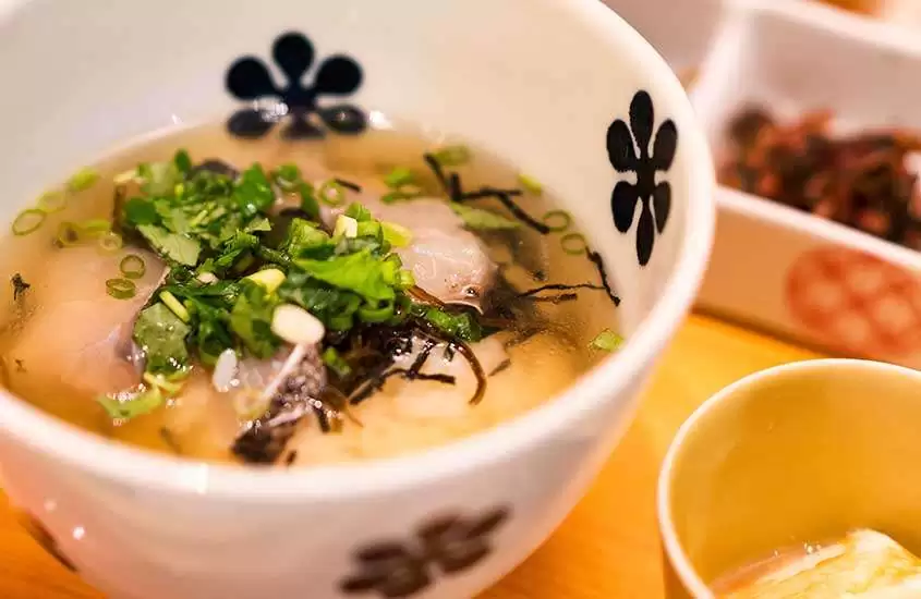Sopa de missô, uma comida da culinária japonesa, servida em uma vasilha branca redonda