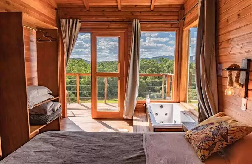 durante o dia, cama de casal e banheira de hidromassagem em chalé de madeira com vista para as montanhas