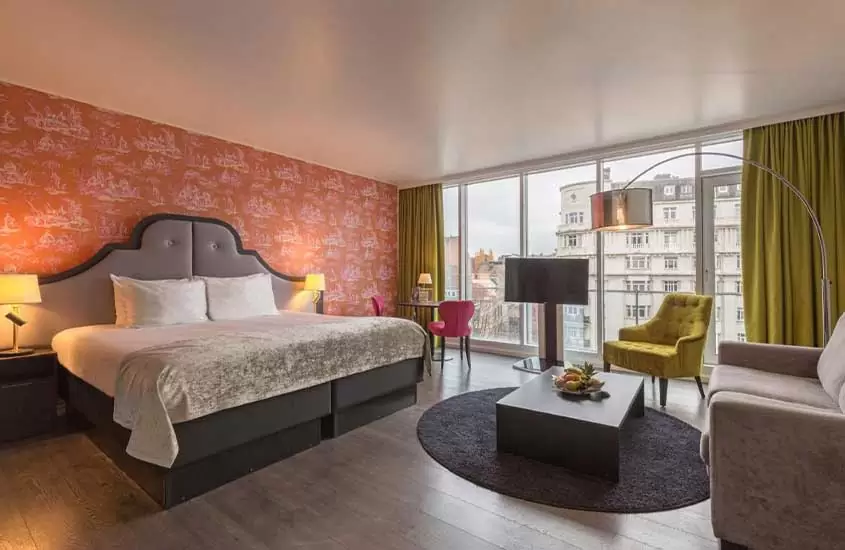 durante o dia, televisão, cama de casal, poltrona e sofá em suíte de hotel em bruxelas com vista panorâmica para a cidade