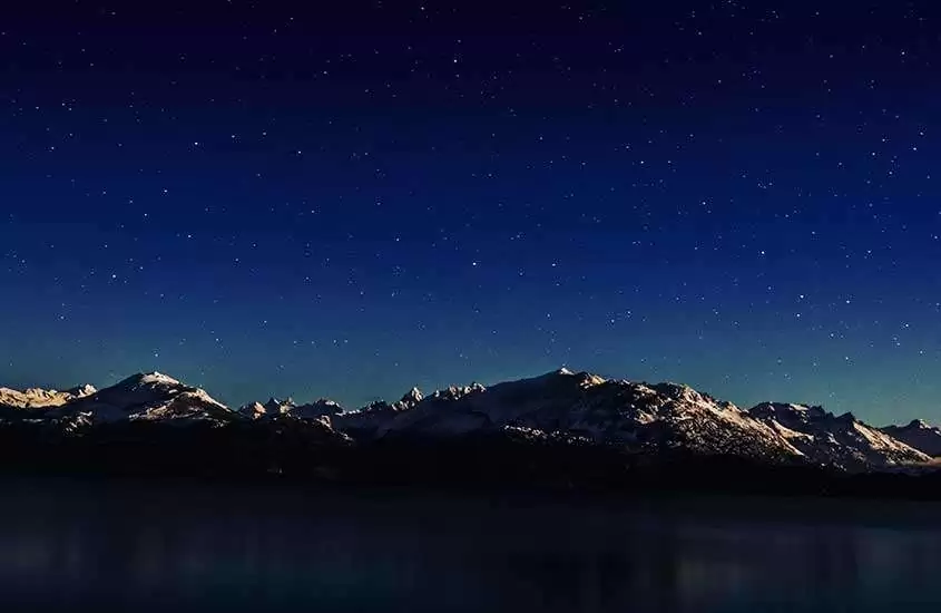 Durante a noite, montanhas nevadas sob um céu estrelado em Bariloche no inverno