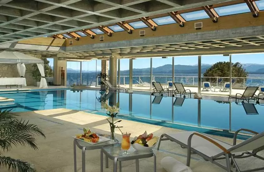 durante o dia, espreguiçadeiras ao redor de grande piscina coberta em hotel com vista para a cidade