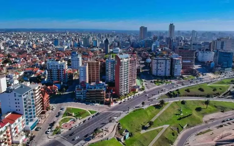 Durante o dia, vista aérea de prédios altos e modernos às margens de avenida movimentada, com carros passando, em Buenos Aires
