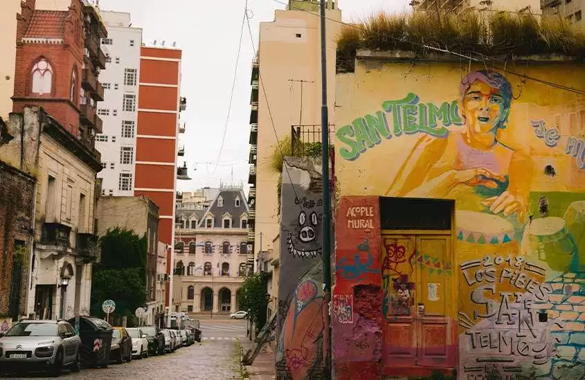 Durante dia nublado, grafites coloridos em casas de San Telmo, bairro histórico e cultural onde ficar em buenos aires