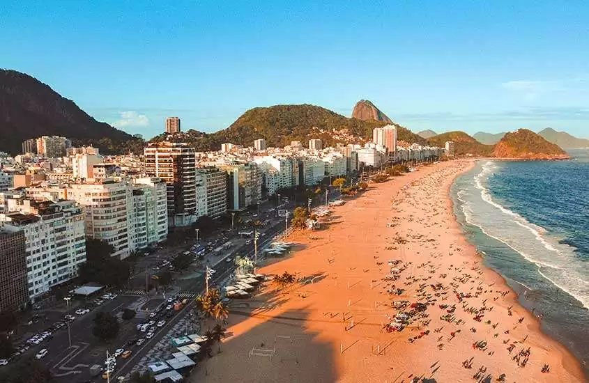 durante dia ensolarado, vista aérea de prédios às margens de praia de Copacabana.