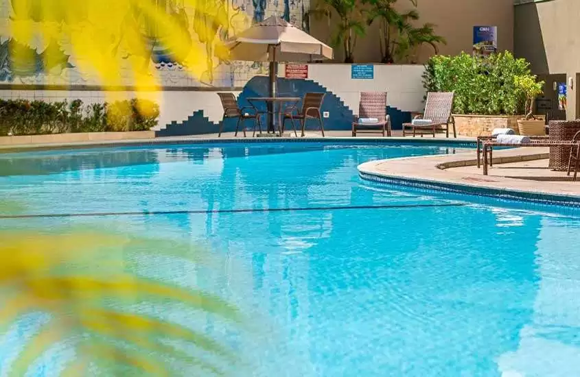 Durante um dia ensolarado, espreguiçadeiras ao redor da piscina ao ar livre de um hotel para passar réveillon em Salvador.