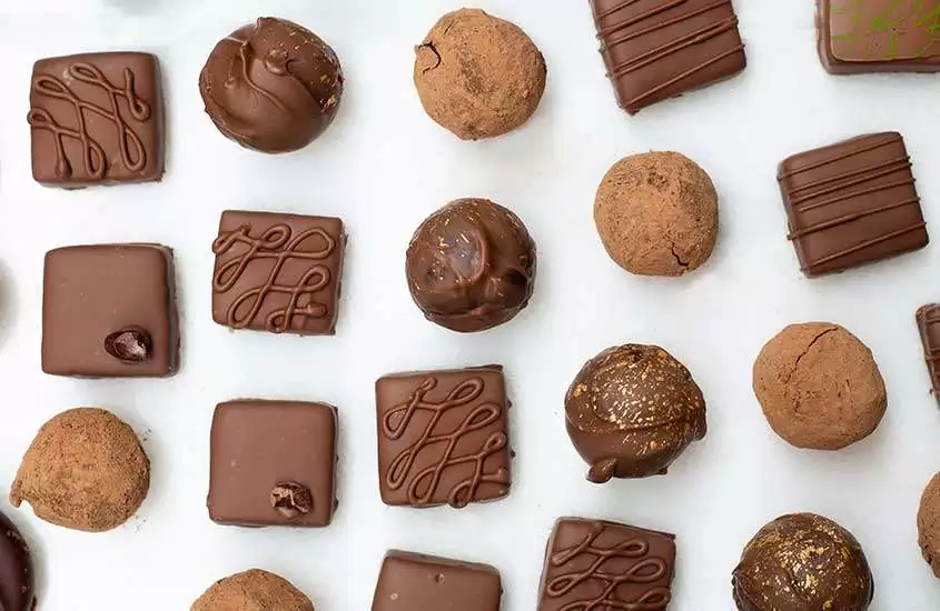 uma variedade de pedaços de chocolate em diferentes tamanhos dispostos sobre uma mesa branca em uma das chocolaterias em bariloche