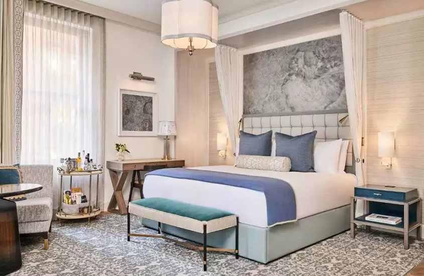 poltrona, mesa e cama de casal em suíte de hotel em nova york