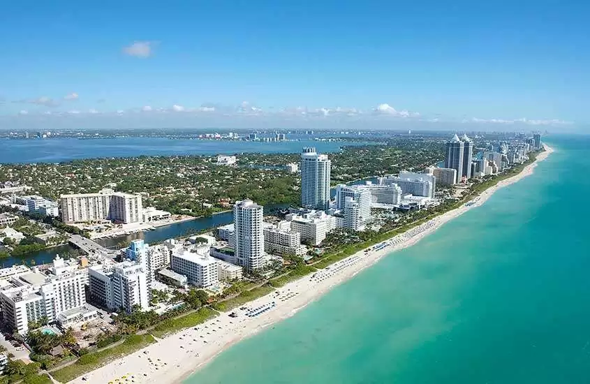 durante o dia, vista aérea de casas e prédios às margens do mar em Miami, uma das cidades da flórida para morar.
