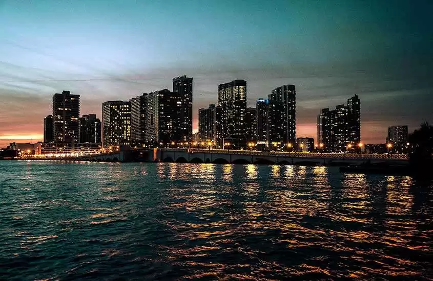 durante a noite, vista panorâmica de prédios iluminados às margens de mar.