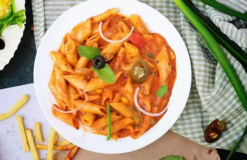 Vista superior de um delicioso prato de macarrão com molho em um prato redondo, criando uma tentadora refeição de comida italiana.