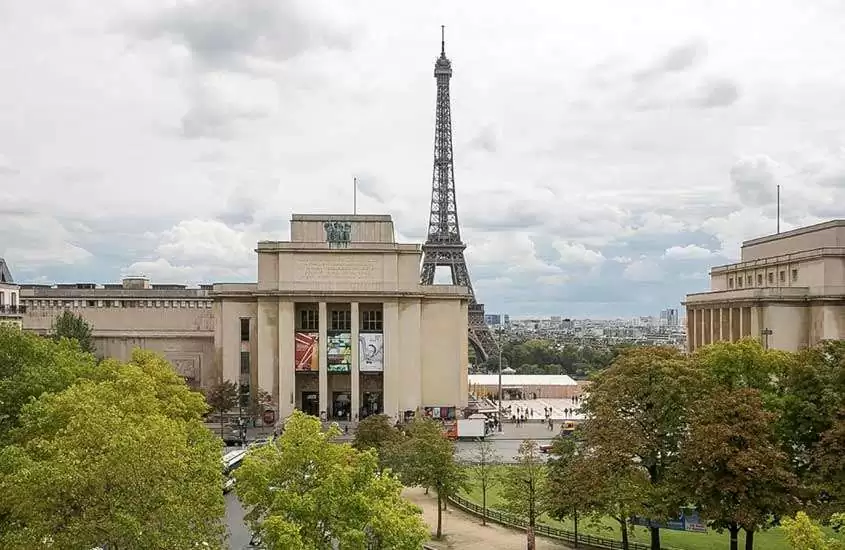 durante um dia nublado, árvores, prédios e Torre Eiffel, vistos de hotel em Paris