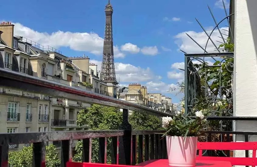 durante o dia, cadeiras e mesas vermelhas em varanda de um dos hotéis em paris com vista para torre eiffel