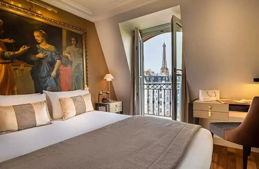 durante o dia, cama de casal, cadeira e mesa em suíte de hotel em Paris com varanda e vista para Torre Eiffel
