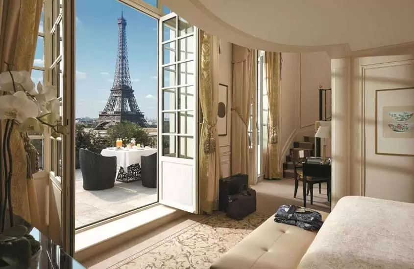 durante um dia ensolarado, cama de casal em suíte com ampla varanda em um hotel em paris com vista para a Torre Eiffel