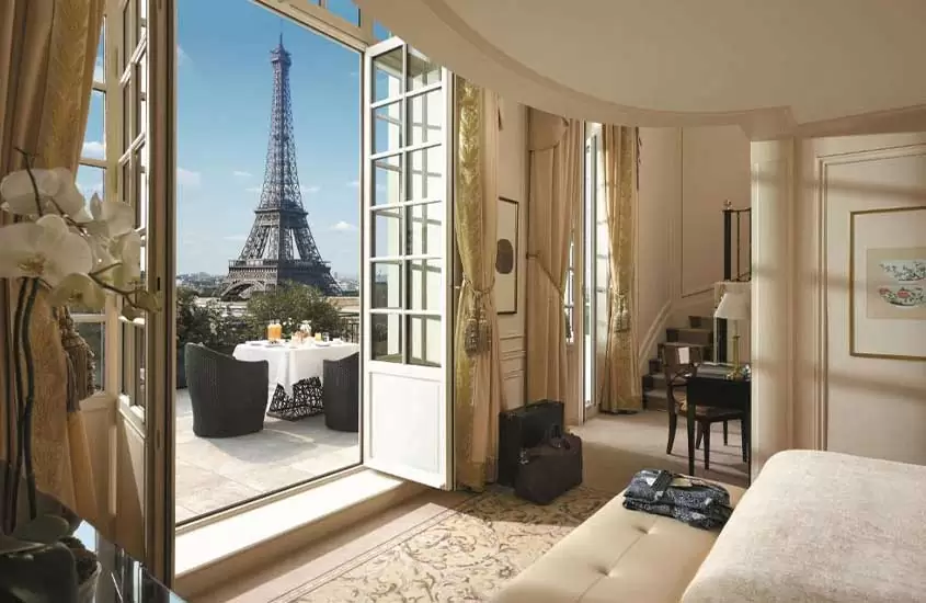 durante um dia ensolarado, cama de casal em suíte com ampla varanda em um hotel em paris com vista para a Torre Eiffel