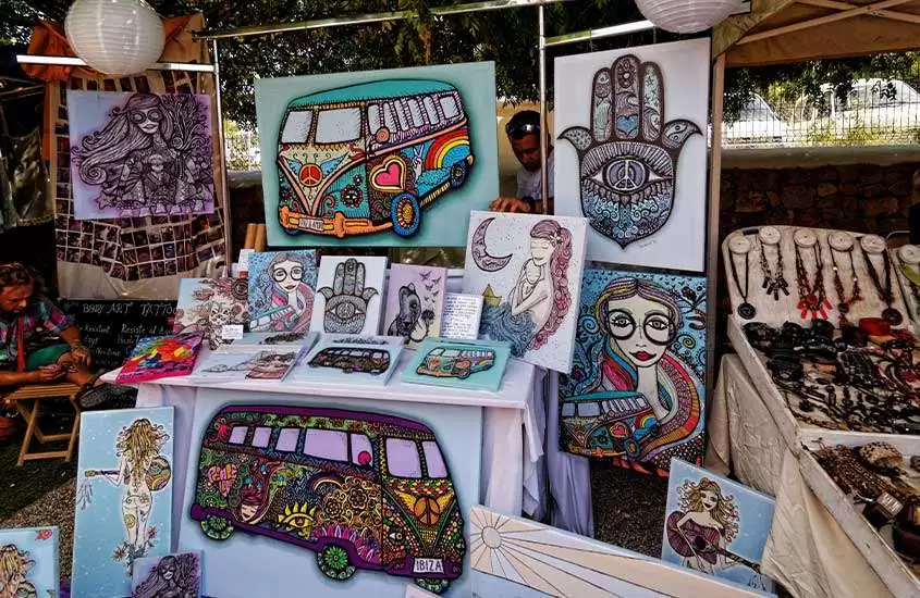 diversos quadros coloridos disponíveis para venda em barraca de feira em Ibiza.