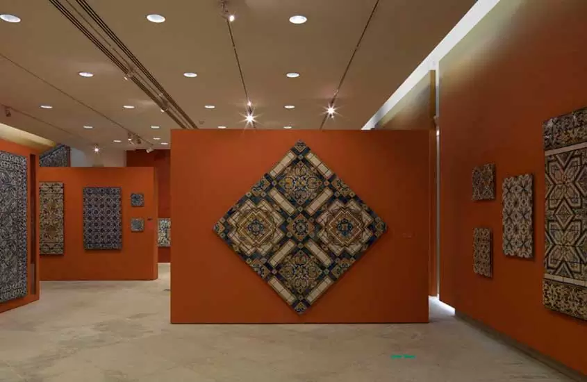 Interior de uma das salas do Museu Nacional do Azulejo em Lisboa com azulejos expostos em paredes laranjas