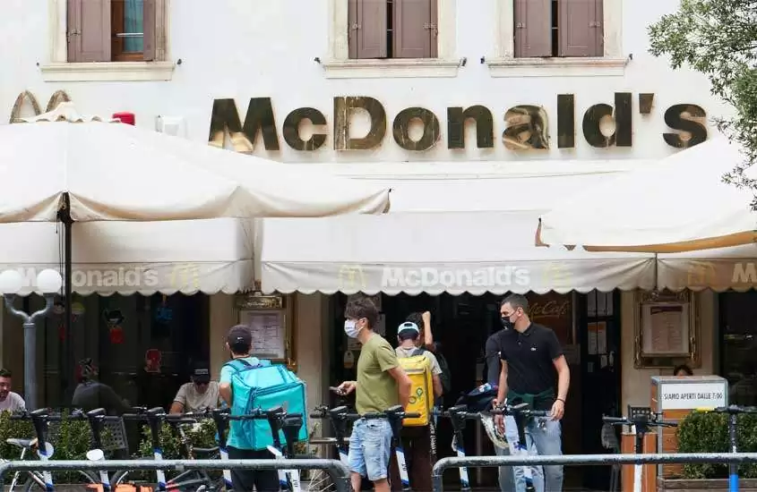 Durante o dia, fachada de um McDonald's em Verona com bicicletas e pessoas na frente