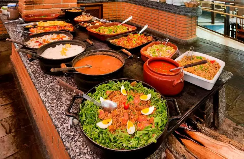 panelas com salada, feijão, arroz e carnes, servidas no balcão de um restaurante de hotel fazenda no interior de São Paulo com opção de pensão completa