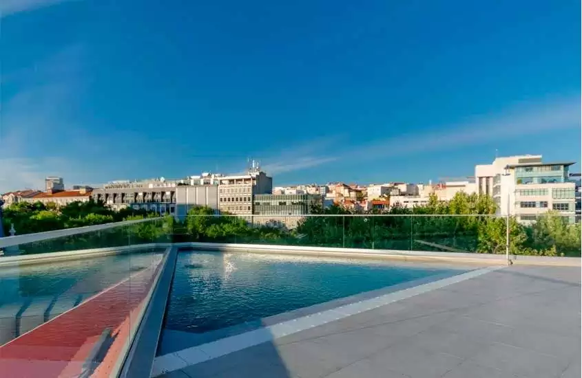 Durante um dia de sol, piscina externa em cobertura de hotel em Lisboa com vista de prédios da cidade