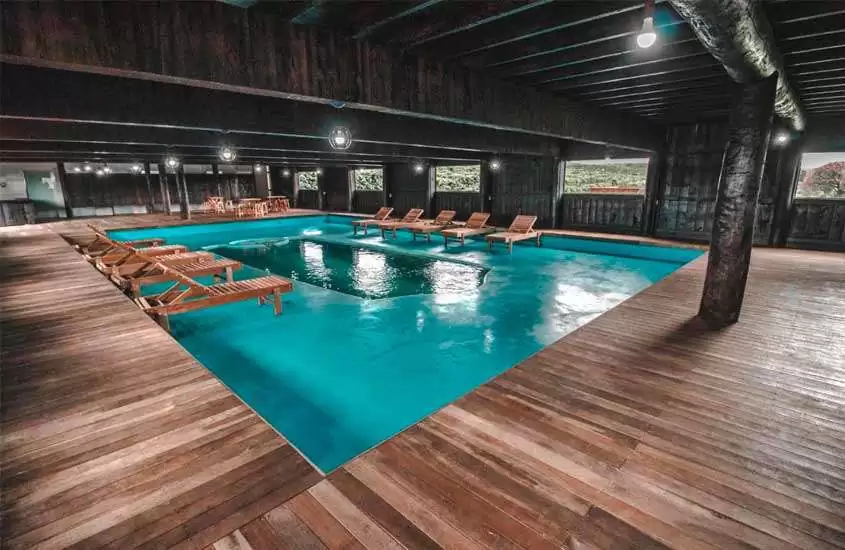 Espreguiçadeiras de madeira em piscina interna e aquecida de um hotel fazenda no interior de São Paulo
