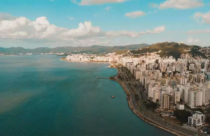 Durante o dia, vista aérea de montanhas, prédios e avenida à beira-mar