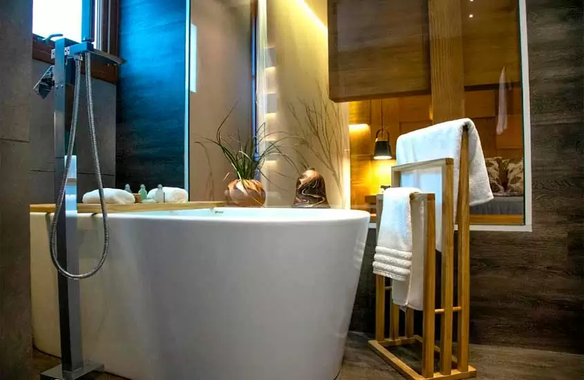 Banheiro de suíte de hotel de luxo em gramado com toalhas e vaso de planta ao lado de banheira